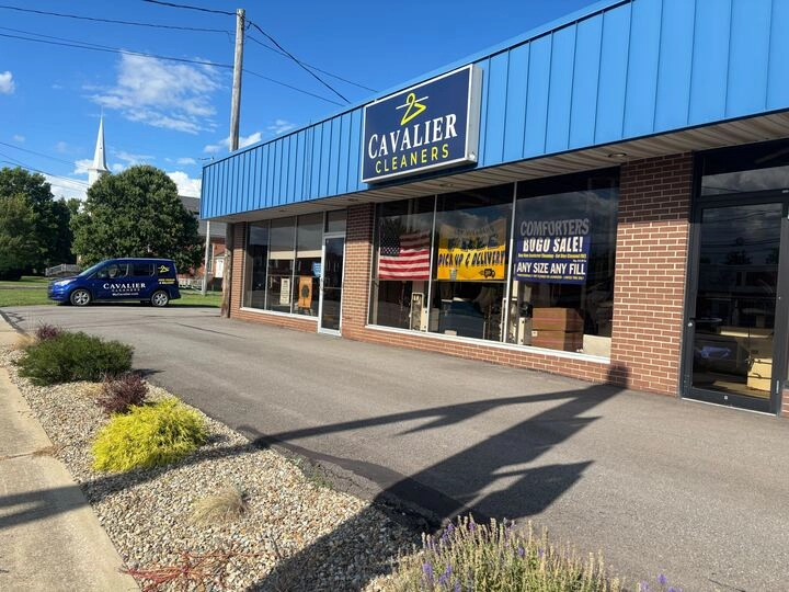 A storefront with a blue sign reading "Cavalier Cleaners," a van parked outside, and a window display advertising a computer sale.