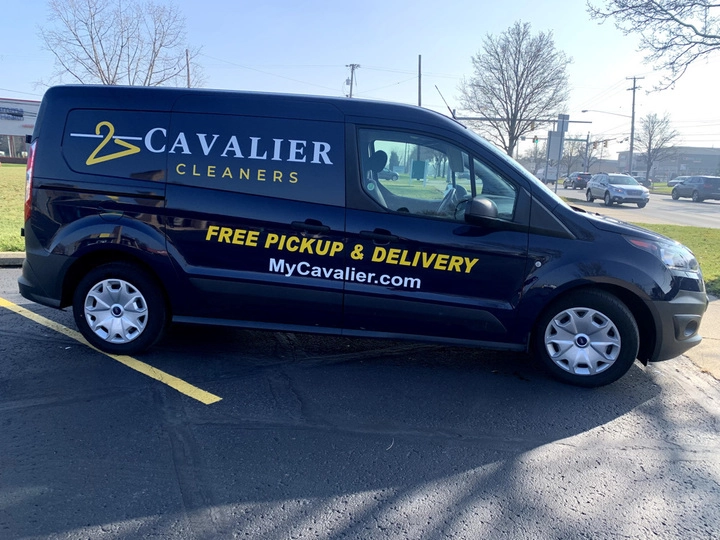 A black Cavalier Cleaners van is parked in a lot. The side displays the company logo, "Free Pickup & Delivery," and the website MyCavalier.com.